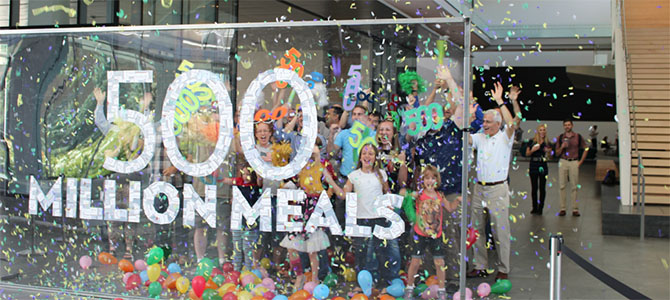 Nu Skin employees and their families pose for a picture to celebrate the donation of 500 million meals through the Nourish the Children initiative.